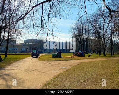 Red tractors trucks in spring city park. Cleaning. Early spring. Works. Sunny spring day. Stock Photo