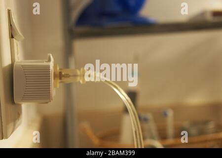 Transparent power cable plugged into a wall socket and light switch combo in my bathroom. Toothbrushes, etc are behind, on the shelf. Stock Photo