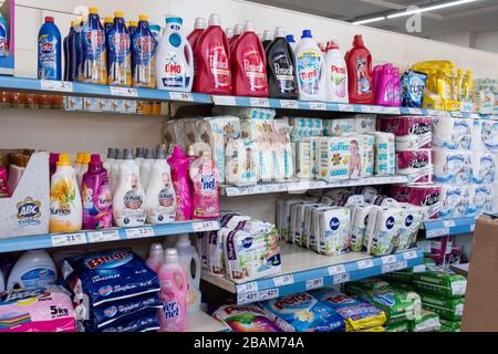 Variety washing-powders, baby diapers and toilet paper on supermarket shelf.