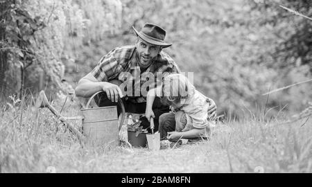 Growing plants. Take care of plants. Boy and father in nature with watering can. Gardening tools. Planting flowers. Dad teaching little son care plants. Little helper in garden. Make planet greener. Stock Photo