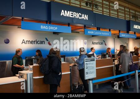 Portland, OR, USA - Feb 16, 2020: Passengers check their baggages at the American Airlines check-in desk in Portland International Airport. Stock Photo