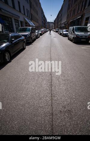 Munich, Germany. 28th Mar, 2020. A woman walks along an almost deserted street in the district of Gärtnerplatz. Credit: Peter Kneffel/dpa/Alamy Live News Credit: dpa picture alliance/Alamy Live News Credit: dpa picture alliance/Alamy Live News Stock Photo