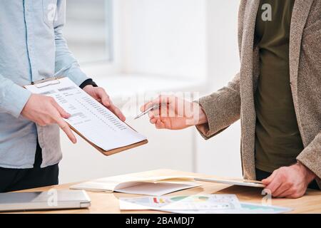 Close-up of unrecognizable colleagues analyzing data while discussing business expenses at meeting Stock Photo