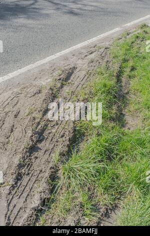 Roadside vehicle skid marks on country road where car has come off the road into the grass verge to avoid something, or as result of hitting a car. Stock Photo