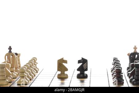 Wooden chess pieces on a chessboard. Black and white chess on chessboard, in white background. Stock Photo