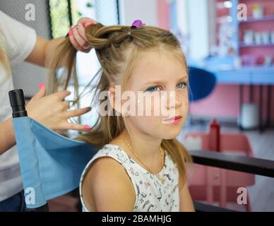 Hairdressing services. Reating hairstyle. Hair styling process. Children hairdressing salon Stock Photo
