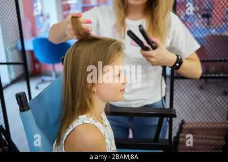 Hairdressing services. Reating hairstyle. Hair styling process. Children hairdressing salon Stock Photo