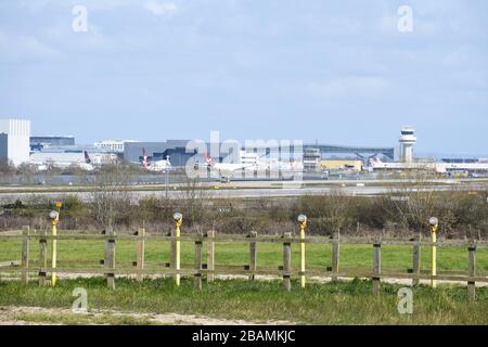 View across runway landing lights to the Gatwick air traffic control tower with Virgin Atlantic and British Airways grounded planes due to Covid-19. Stock Photo