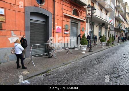 Pagani,Sa,Italy - March 28,2020 :Persons queuing outside the Italian Post Office to be able to pick up their pension or pay bills respecting the secur Stock Photo