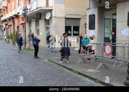 Pagani,Sa,Italy - March 28,2020 :Persons queuing outside the Italian Post Office to be able to pick up their pension or pay bills respecting the secur Stock Photo