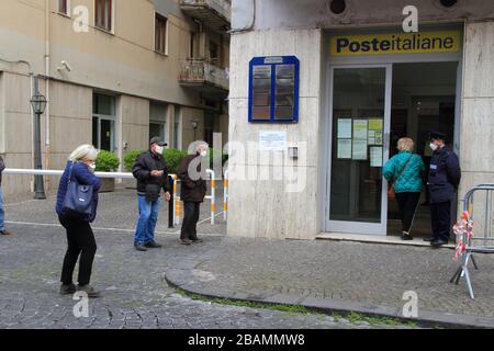 Pagani,Sa,Italy - March 28,2020 :Persons queuing outside the Italian Post Office to be able to pick up their pension or pay bills respecting the secur Stock Photo