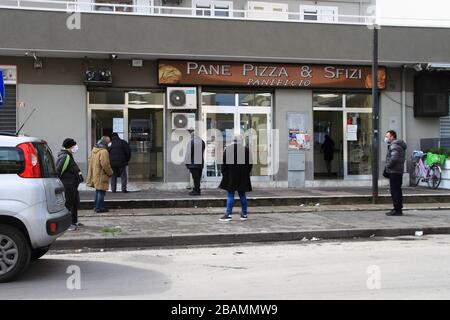 Pagani,Sa,Italy - March 28,2020 :People lining up at a bakery to buy bread and other over-the-counter products observing the safety distances establis Stock Photo