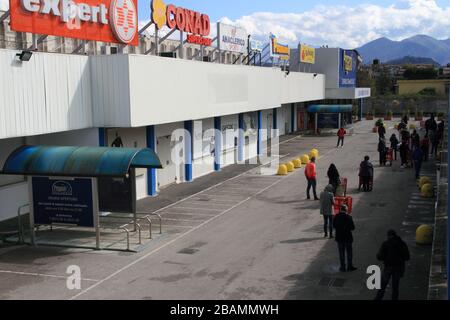 Pagani,Sa,Italy- March 28,2020: A long line of people waiting to enter the shopping center to make purchases respecting the stable distances from the Stock Photo