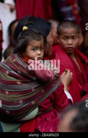 A Bhutanese mother carries her child in a sling on her back during Bhutan's annual Thimphy Tsechu festival.  (12-10-89) BX61 Stock Photo