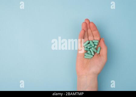 Top above overhead pov close up view photo of hands holding handful of pills isolated on blue background with blank copy empty space Stock Photo