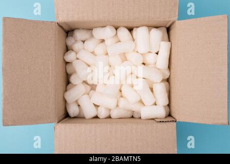 Top overhead close-up view photo of filler in cardboard box on blue background Stock Photo