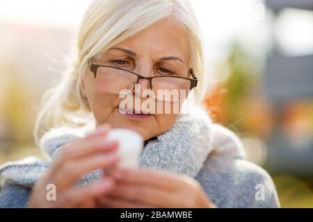Senior woman taking prescription medicine outdoors Stock Photo