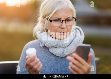 Senior woman taking prescription medicine outdoors Stock Photo