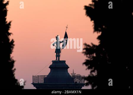 Statue on top of bell tower at Church of Sant'Alessandro della Croce silhouetted against sunrise, Bergamo, Italy Stock Photo