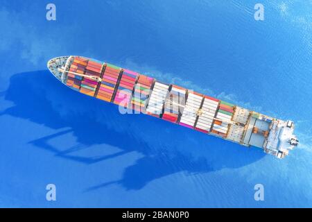 Large full loaded container ship sailing bright blue sea. Top aerial view Stock Photo