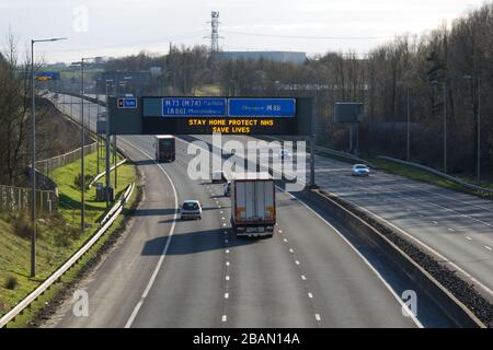 Glasgow, UK. 28th Mar, 2020. Pictured: Road signs all along the M8 and M80 motorways which read, “STAY HOME PROTECT NHS SAVE LIVES” The Coronavirus Pandemic has forced the UK Government to order a shut down of all the UK major cities and make people stay at home, which has left the motorways and all other roads free of the usual nose to tail traffic which would otherwise be there. Credit: Colin Fisher/Alamy Live News Stock Photo