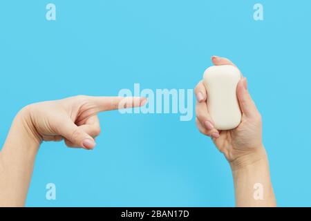 Hand hygiene concept. female hand points to antibacterial soap on a blue background. Hand antiseptic during the coronovirus pandemic Stock Photo