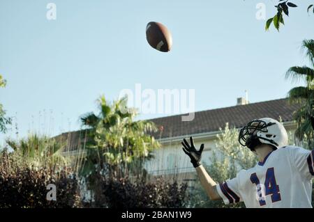 American football player in a game. Player catching an American football ball in a park. Stock Photo
