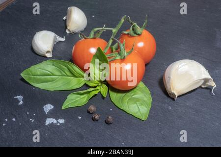 Cherry tomatoes and basil leaves on black background Stock Photo