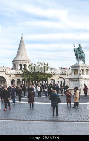 Budapest, Hungary - Nov 6, 2019: Fishermans Bastion in the Hungarian city. One of the best-known monuments in town, built in Neo-Romanesque style. Tourists sightseeing. St. Stephen equestrian statue. Stock Photo