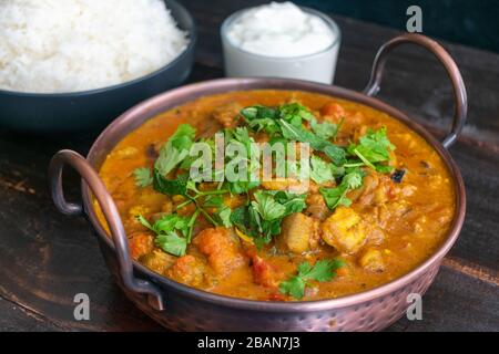 Curried Roasted Eggplant with Smoked Cardamom and Coconut Milk: Eggplant curry topped with mint and cilantro shown with basmati rice and yogurt in the Stock Photo