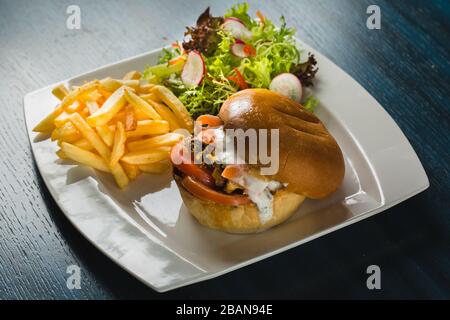 Two craft beef burgers on wooden table on blue background. Stock Photo