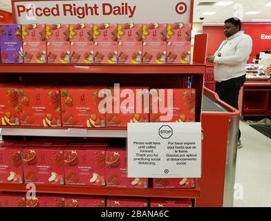 A sign advises grocery shoppers to stop before the checkout and wait for cashier to call them forward to help practice social distancing at a Target in the San Francisco Bay Area, printed in Spanish and English. Stock Photo