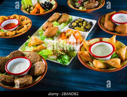 Table served with middle eastern traditional dishes. Bowl with falafel, doner kebap, vegetarian pita, hummus, tabbouleh bulgur salad, chickpea, olive Stock Photo