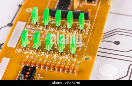 Green rectangular light-emitting diodes in rows on circuit board. Electronic components. Plastic LED lights, switch, resistor. Flex keyboard membrane. Stock Photo