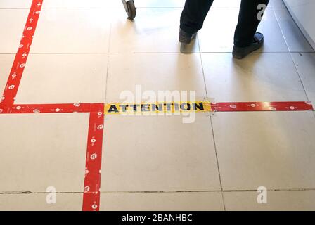 Montreal, Canada - March 28, 2020: Attention line on floor in store to keep social distancing. Social distancing is deliberately increasing the physic Stock Photo