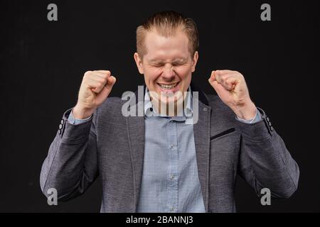 A man in a jacket enjoys good luck, success, breakthrough on a black background. Close up. Stock Photo