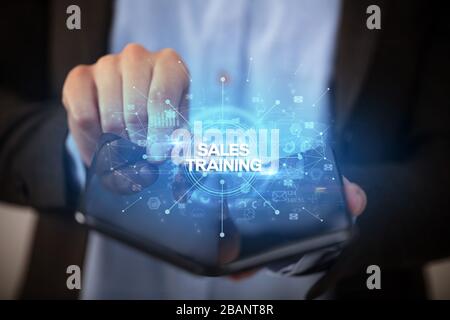 Businessman holding a foldable smartphone with SALES TRAINING inscription, new business concept