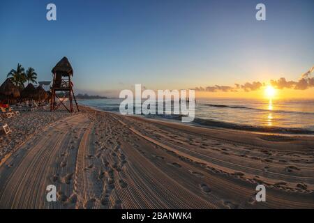 Golden sunrise over tropical beaches of Riviera Maya near Cancun, Mexico, with lifeguard tower overlooking the Caribbean Sea. Stock Photo