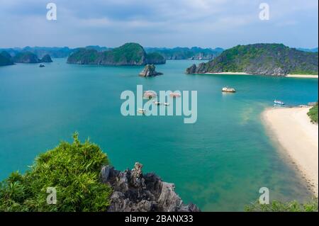 very picturesque bay, moored ships and sandy beach. Panorama from Monkey Island in Ha Long Bay with karst stone islands in the sea. Vietnam Stock Photo