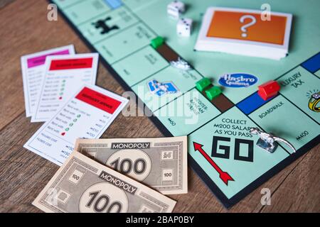 Closeup of Monopoly board game isolated on a wooden background. The classic fast-dealing property trading board game is currently published by Hasbro. Stock Photo