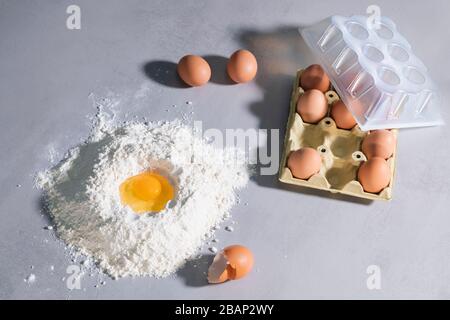 Egg in flour with eggshells and carton of eggs Stock Photo