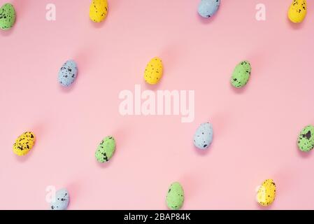 Multi-colored quail eggs on a pink background. Yellow, blue and green little easter eggs. Seamless pattern. Stock Photo