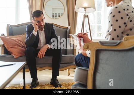 Sad Caucasian man staring at his psychotherapist Stock Photo