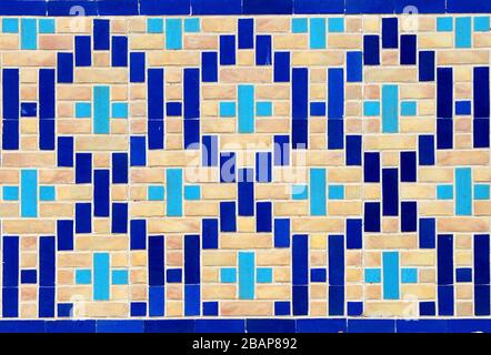 Symmetric ceramic tiles in Ulugh Beg Madrasah. Located in the Registan Square, Samarkand, Uzbekistan. Ceramic in shades of cyan and blue in brick wall. Stock Photo