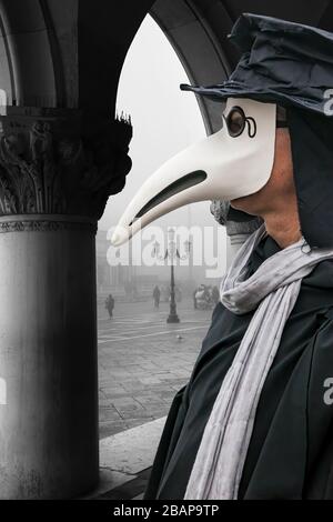 Plague doctor against gondolas during foggy day in Venice, Italy, Epidemic symbol Stock Photo