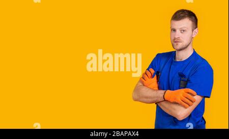 Young male worker in gloves and overalls. Male repair specialist. Professional for work. Yellow background Stock Photo