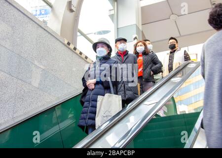 People wearing protective masks riding an escalator, during the Coronavirus pandemic, Seoul, South Korea Stock Photo