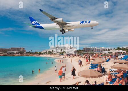 An Air France JOON Airbus A340-300 sails over tourists on Maho Beach, St. Maarten Stock Photo