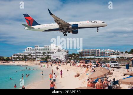 A Delta Air Lines Boeing 757 flies over tourists on Maho Beach while landing at SXM