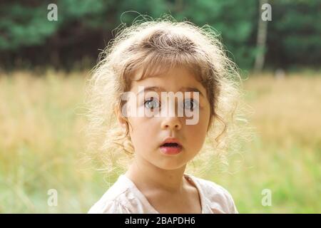 Close up Portrait of beautiful little Girl  surprised with something at summer day Stock Photo